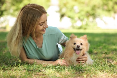 Photo of Young woman with her cute dog on green grass in park