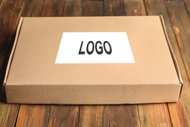 Image of Closed cardboard box with logo on brown wooden table