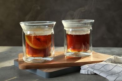 Photo of Wooden board with glasses of hot tea on table