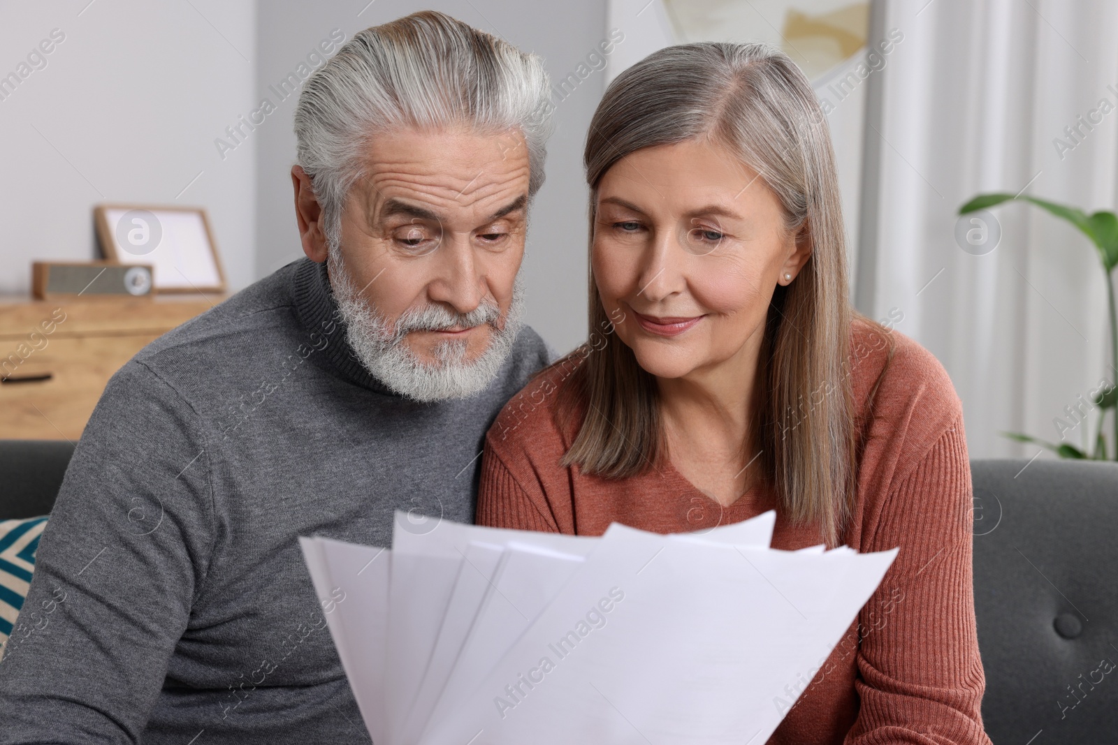 Photo of Elderly couple with papers discussing pension plan in room