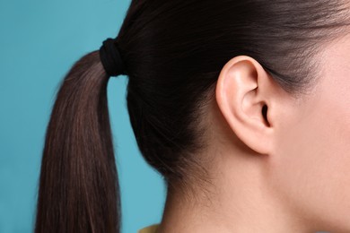 Photo of Woman on light blue background, closeup of ear
