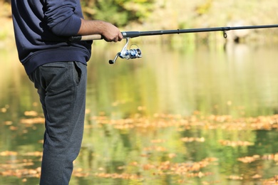 Photo of Man fishing alone at riverside on sunny day, closeup