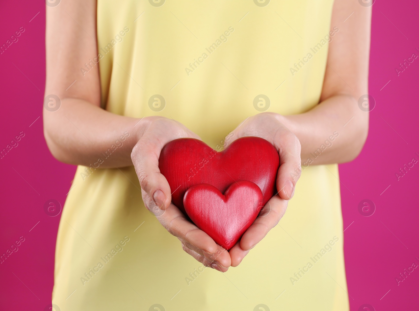 Photo of Woman holding decorative hearts on color background, closeup