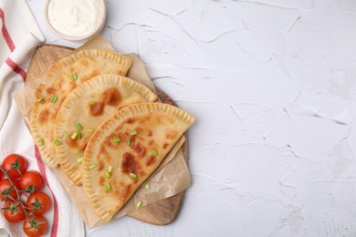 Delicious fried chebureki with cheese, green onion, tomatoes and sauce on white textured table, flat lay. Space for text