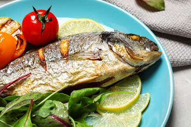 Photo of Delicious roasted fish with lemon and vegetables on plate, closeup