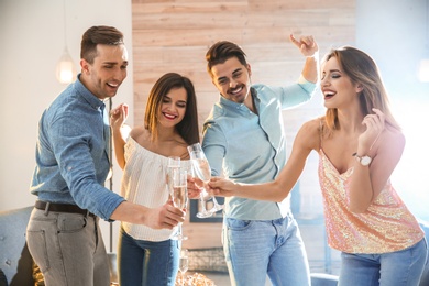 Friends clinking glasses with champagne at party indoors