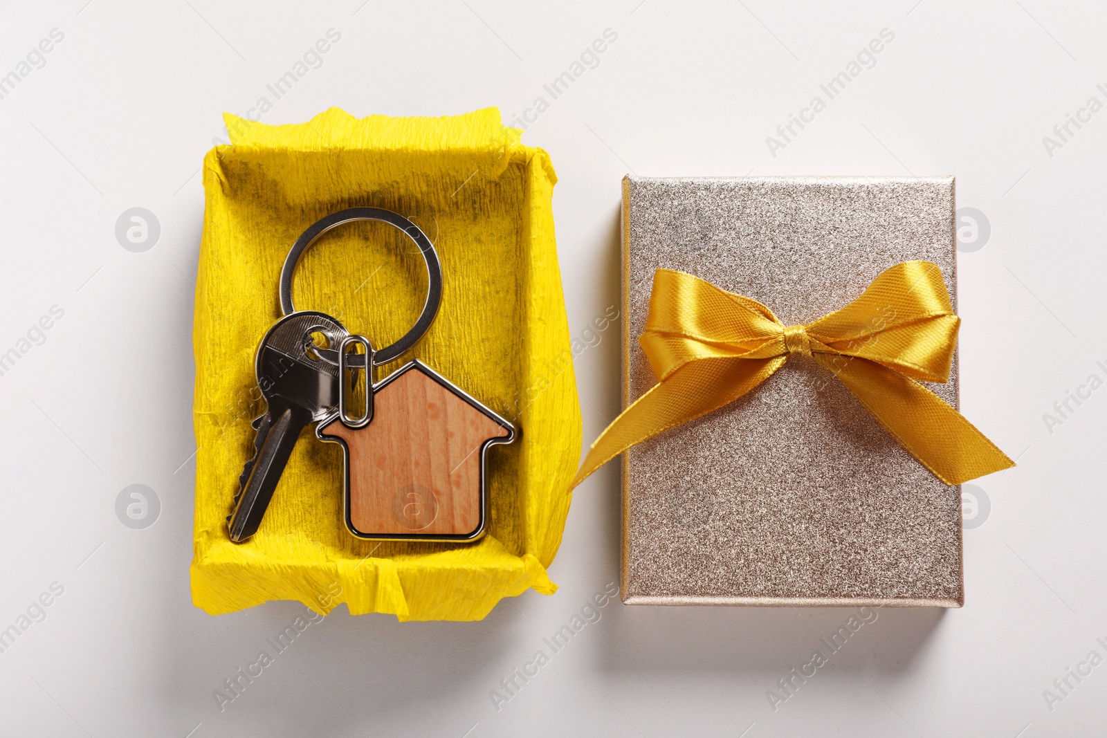 Photo of Key with trinket in shape of house and gift box on light grey background, flat lay. Housewarming party