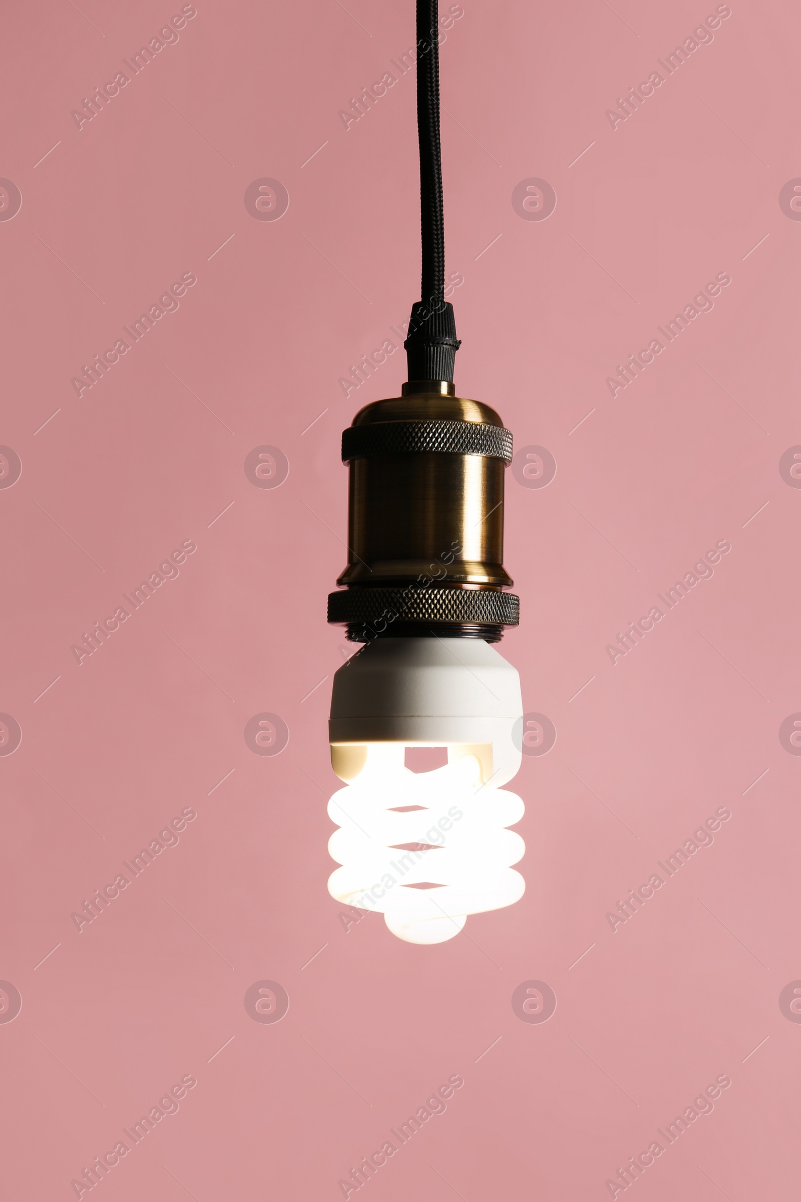 Photo of Hanging fluorescent lamp bulb against pink background
