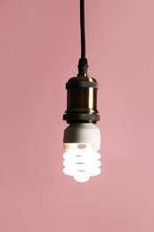 Hanging fluorescent lamp bulb against pink background