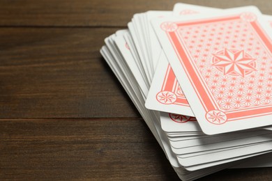 Photo of Deck of playing cards on wooden table, closeup. Space for text