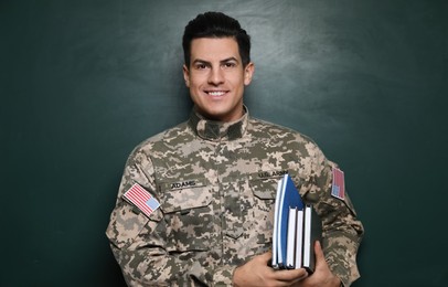 Photo of Cadet with books near chalkboard. Military education