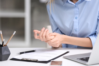 Photo of Young woman suffering from wrist pain in office