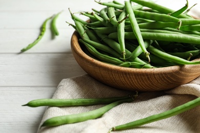 Photo of Fresh green beans in bowl on white wooden table, closeup