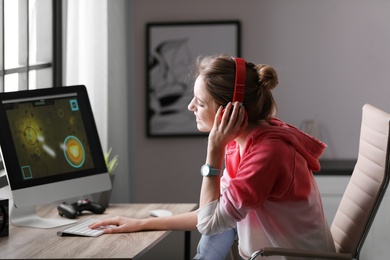 Photo of Young woman playing video game at home