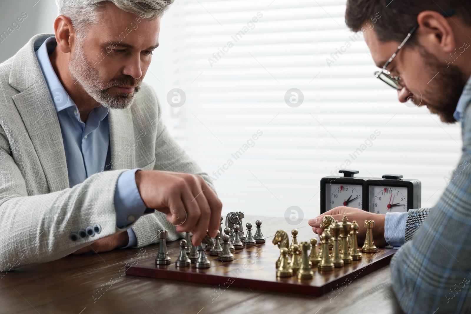 Photo of Men playing chess during tournament at table indoors