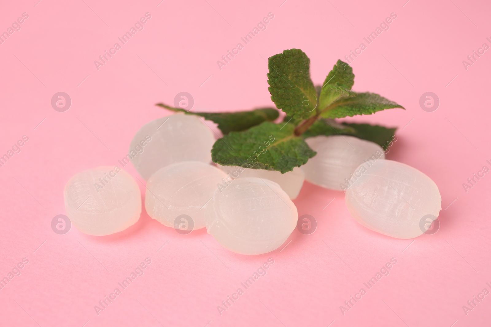 Photo of Cough drops and mint leaves on pink background