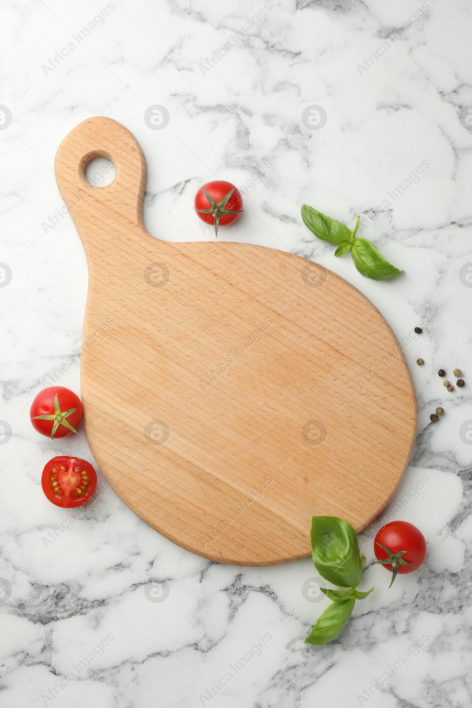 Photo of Cutting board, basil, spices and tomatoes on white marble table, flat lay. Space for text