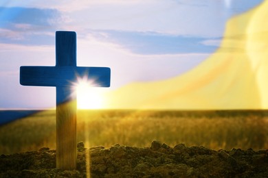 Image of Pray for Ukraine. Double exposure of cross outdoors and Ukrainian flag