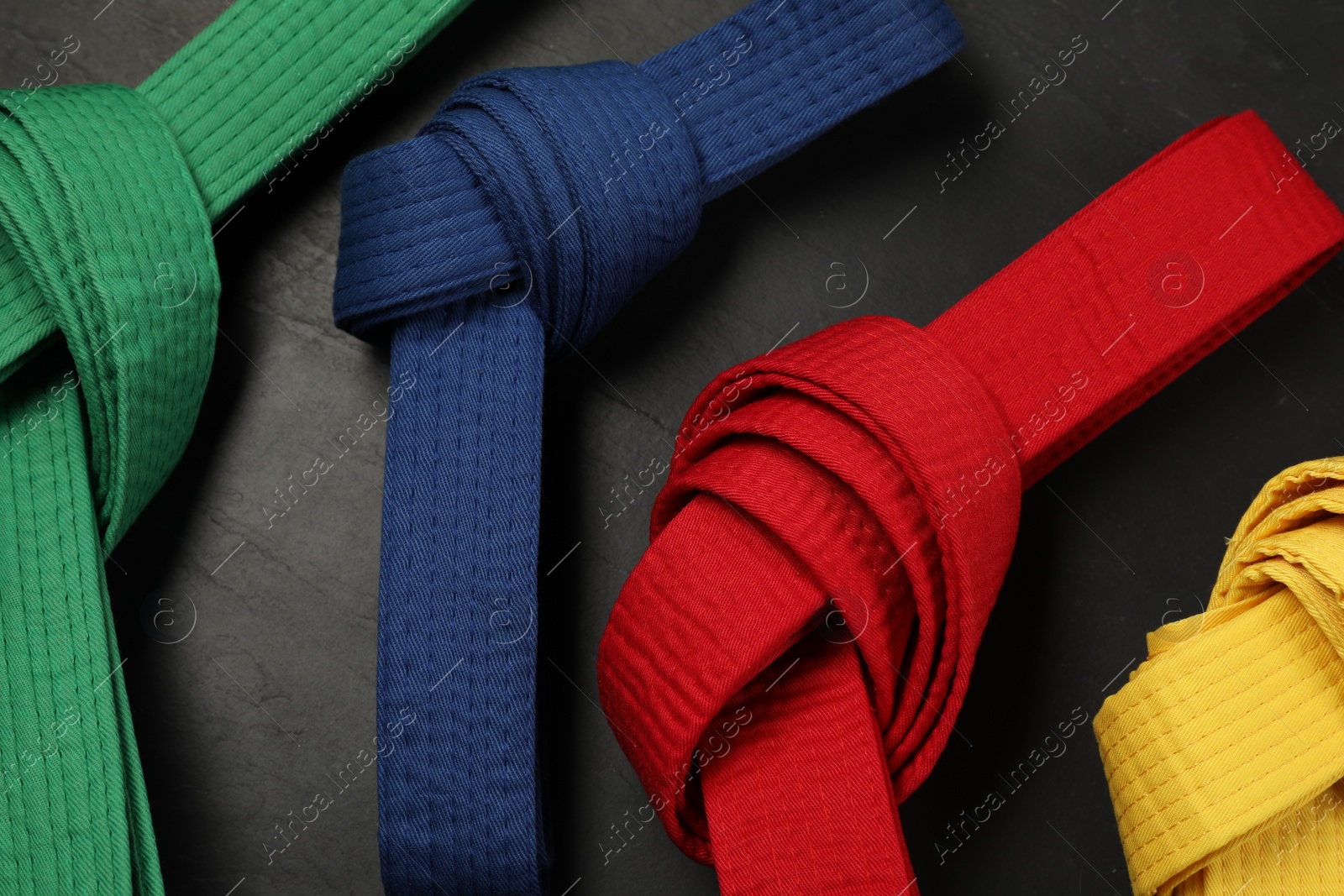 Photo of Colorful karate belts on gray background, flat lay