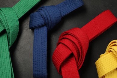 Photo of Colorful karate belts on gray background, flat lay