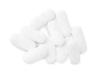 Photo of Pile of calcium supplement pills on white background, flat lay