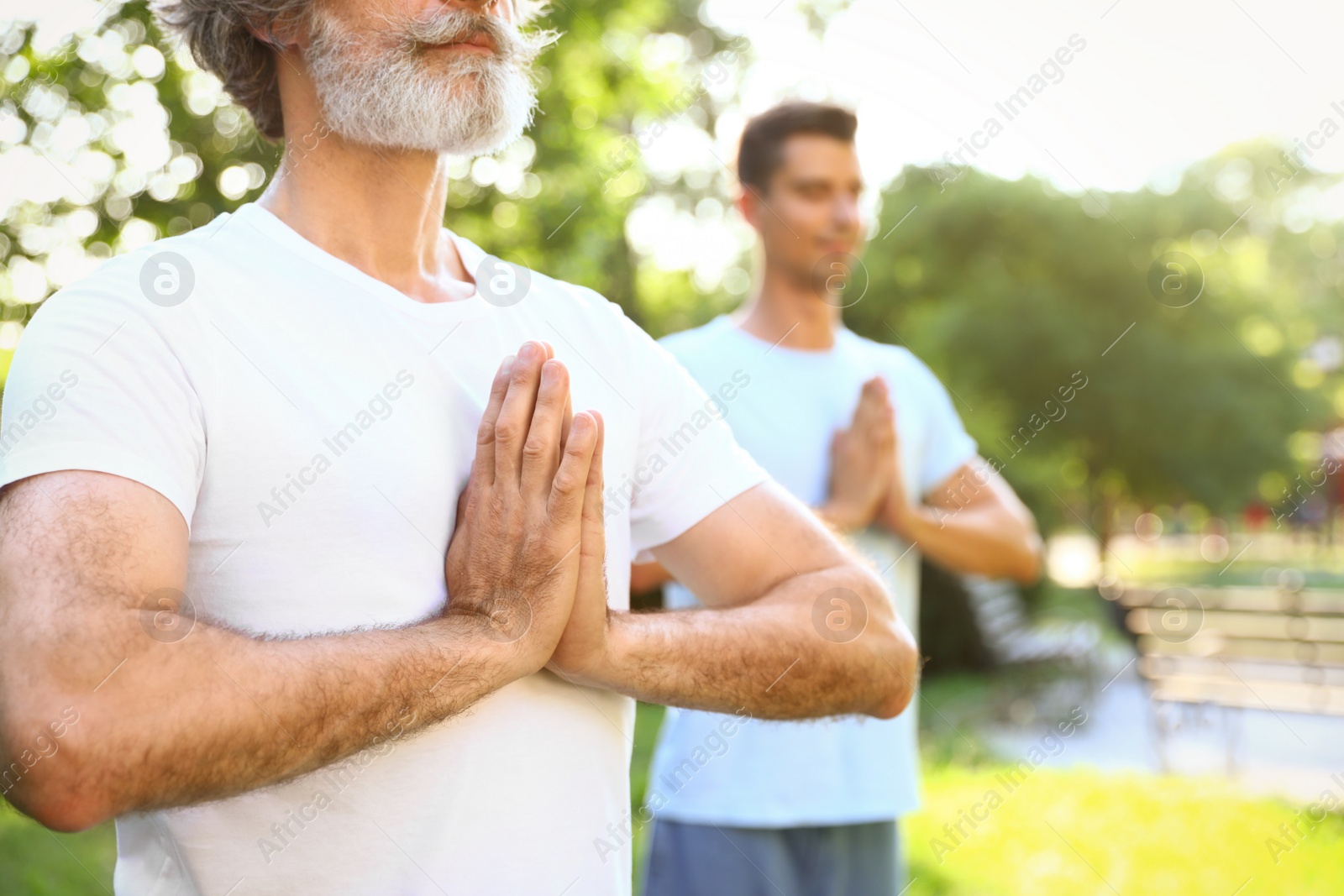 Photo of Men practicing morning yoga in sunny park