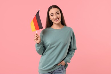 Young woman holding flag of Germany on pink background