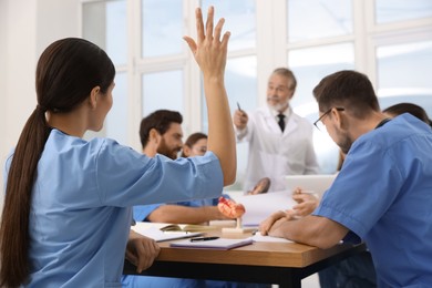 Photo of Intern raising hand to ask doctor question at lecture in hospital