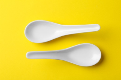 Photo of Miso soup spoons on yellow background, flat lay