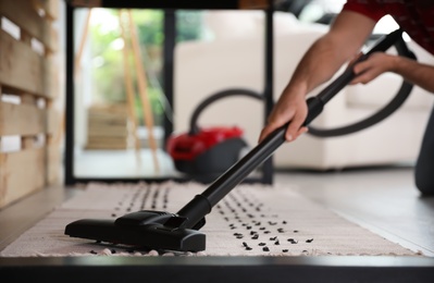 Photo of Young man using vacuum cleaner at home, closeup