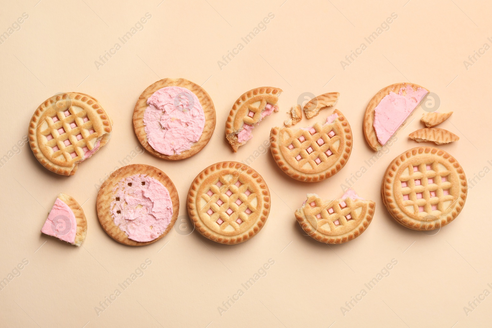 Photo of Tasty sandwich cookies with cream on beige background, flat lay