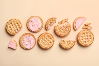 Photo of Tasty sandwich cookies with cream on beige background, flat lay