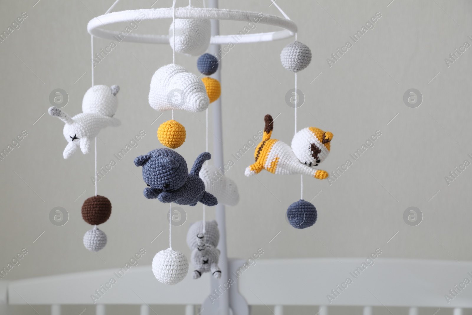 Modern baby crib mobile near beige wall in room. Space for text Photo of Modern baby crib mobile near beige wall in room. Space for text