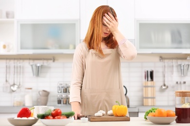 Photo of Tired housewife cooking in kitchen