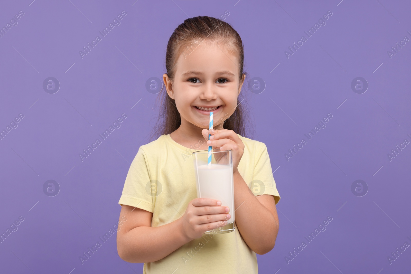 Photo of Cute girl with glass of fresh milk on violet background