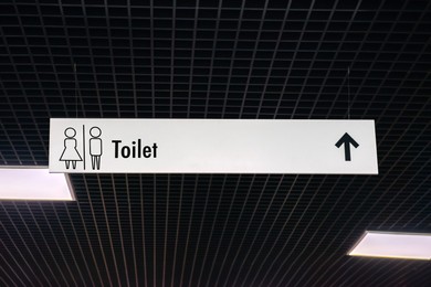 Image of Hanging sign of public toilet with arrow showing direction