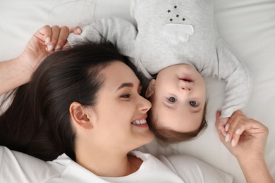 Portrait of mother with her cute baby lying on bed, top view