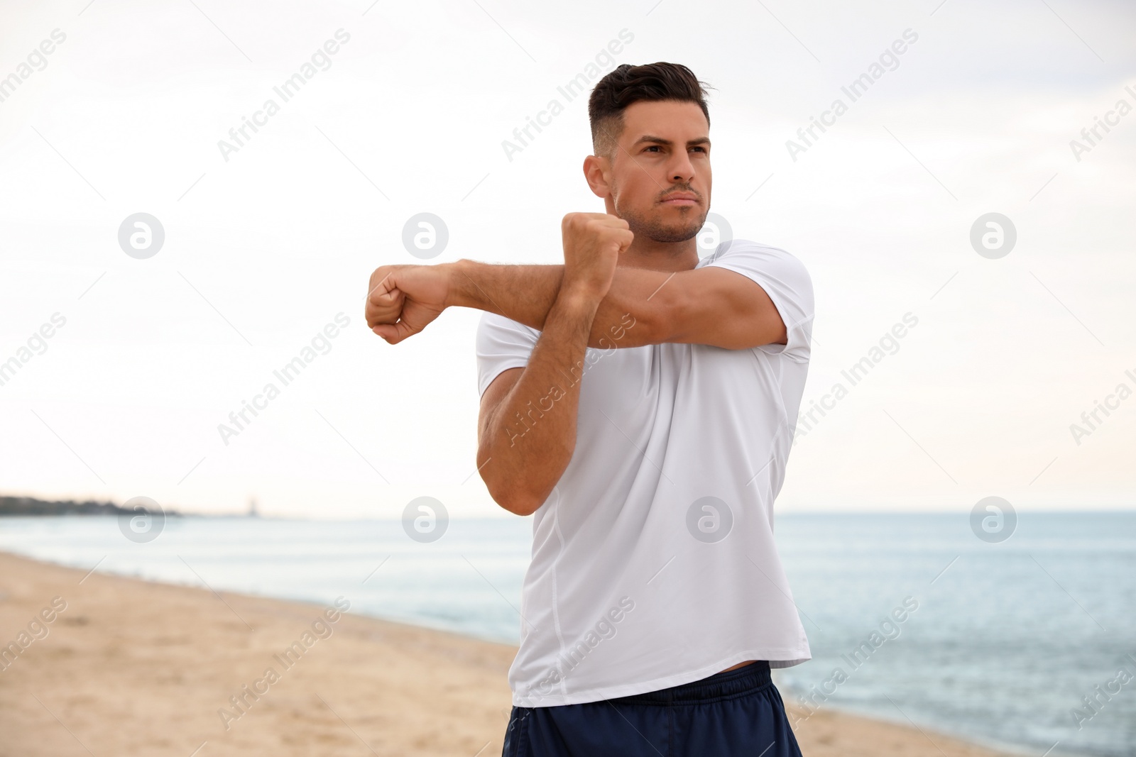 Photo of Muscular man doing exercise on beach. Body training