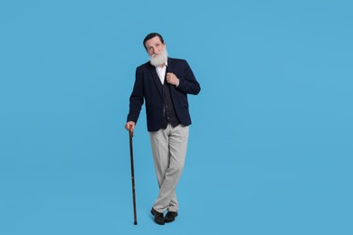 Senior man with walking cane on light blue background