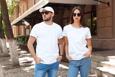 Photo of Young couple wearing white t-shirts on street