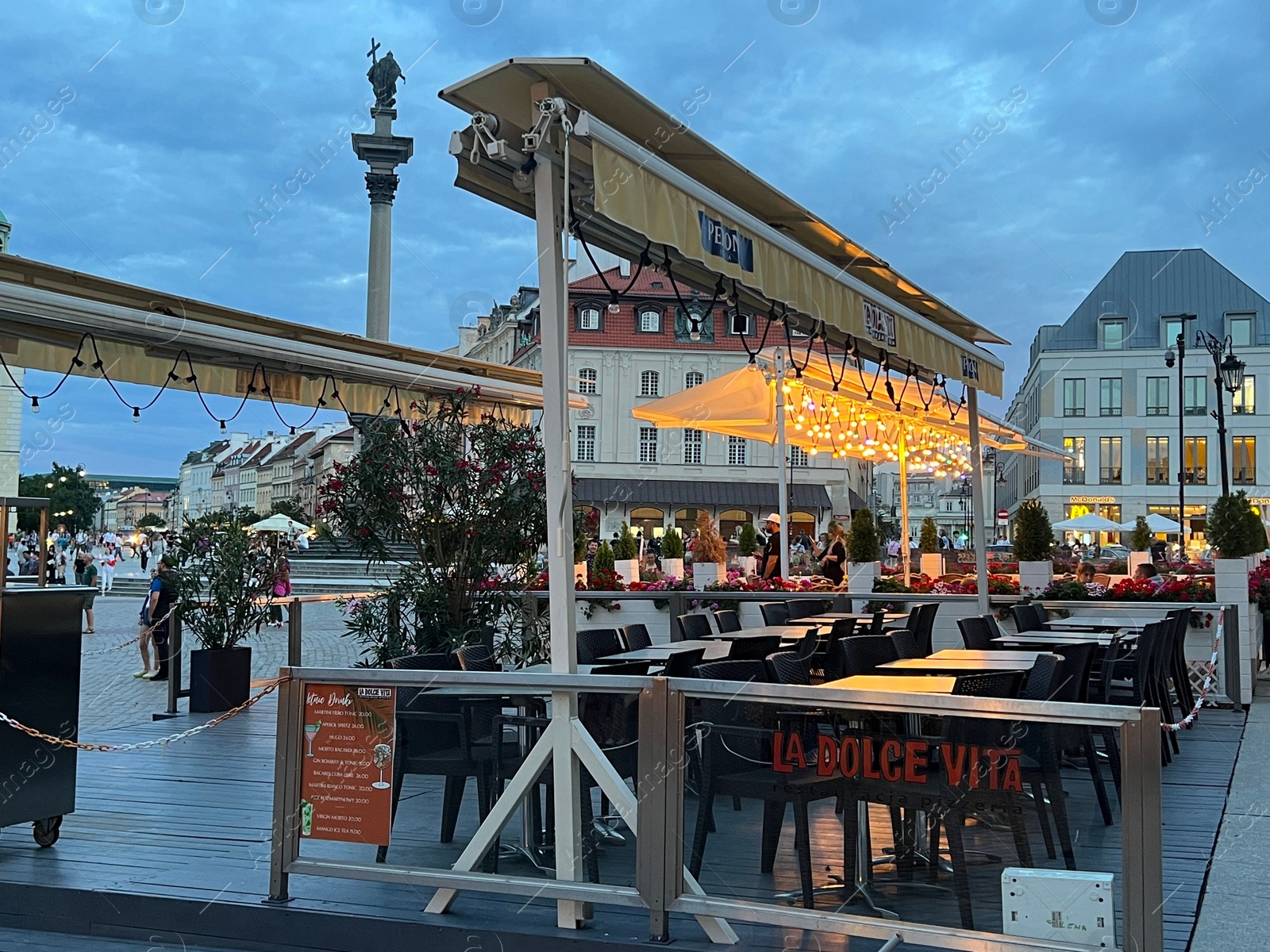 Photo of WARSAW, POLAND - JULY 15, 2022: Outdoor cafe terraces on Crowded Old Town Market Place in evening