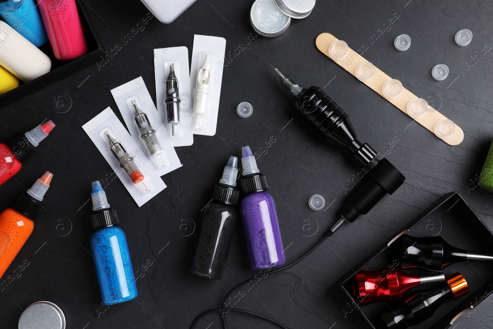 Photo of Flat lay composition with tattoo equipment on black table