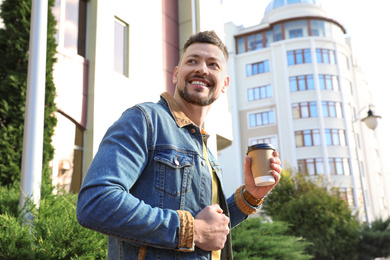 Photo of Man with cup of coffee on city street in morning