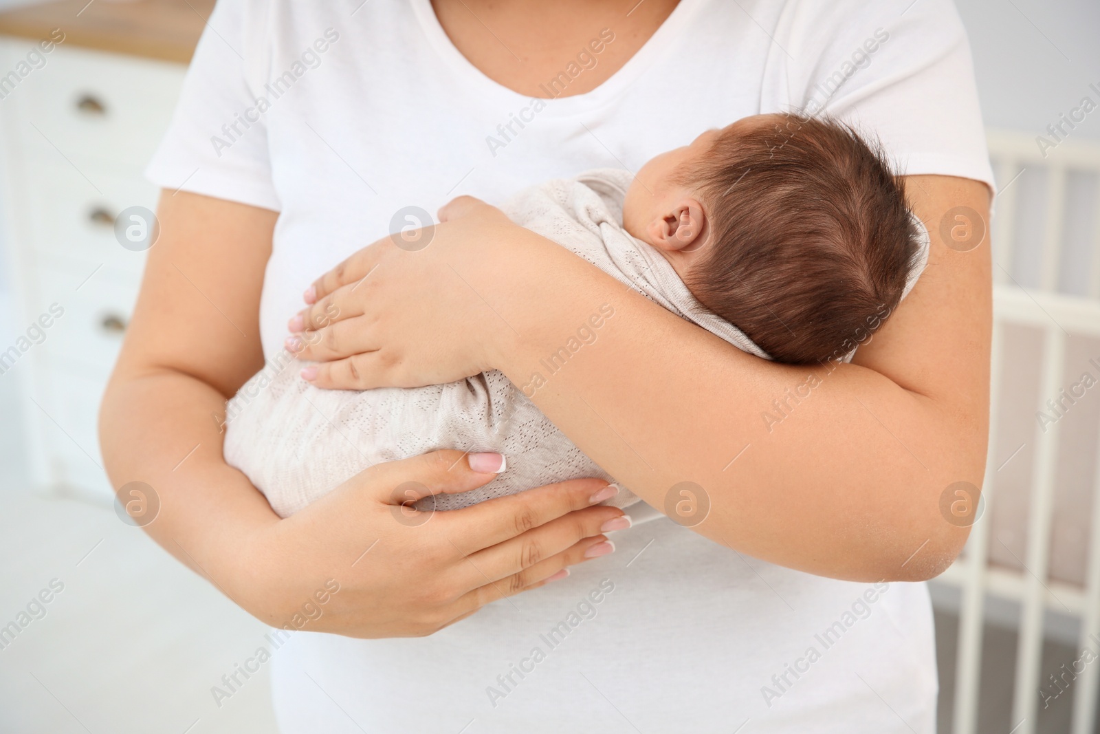 Photo of Young mother holding cute newborn baby, closeup