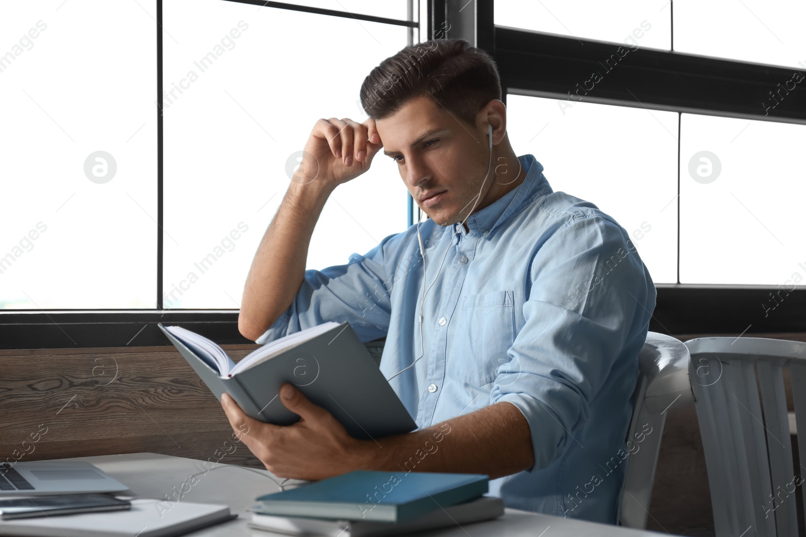 Photo of Man listening to audiobook at table in cafe