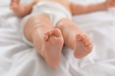 Cute little baby lying on bed, closeup of legs