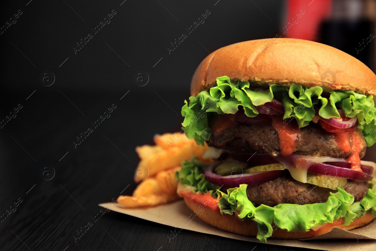 Photo of Tasty burger with vegetables, patties and lettuce served on wooden table, closeup. Space for text