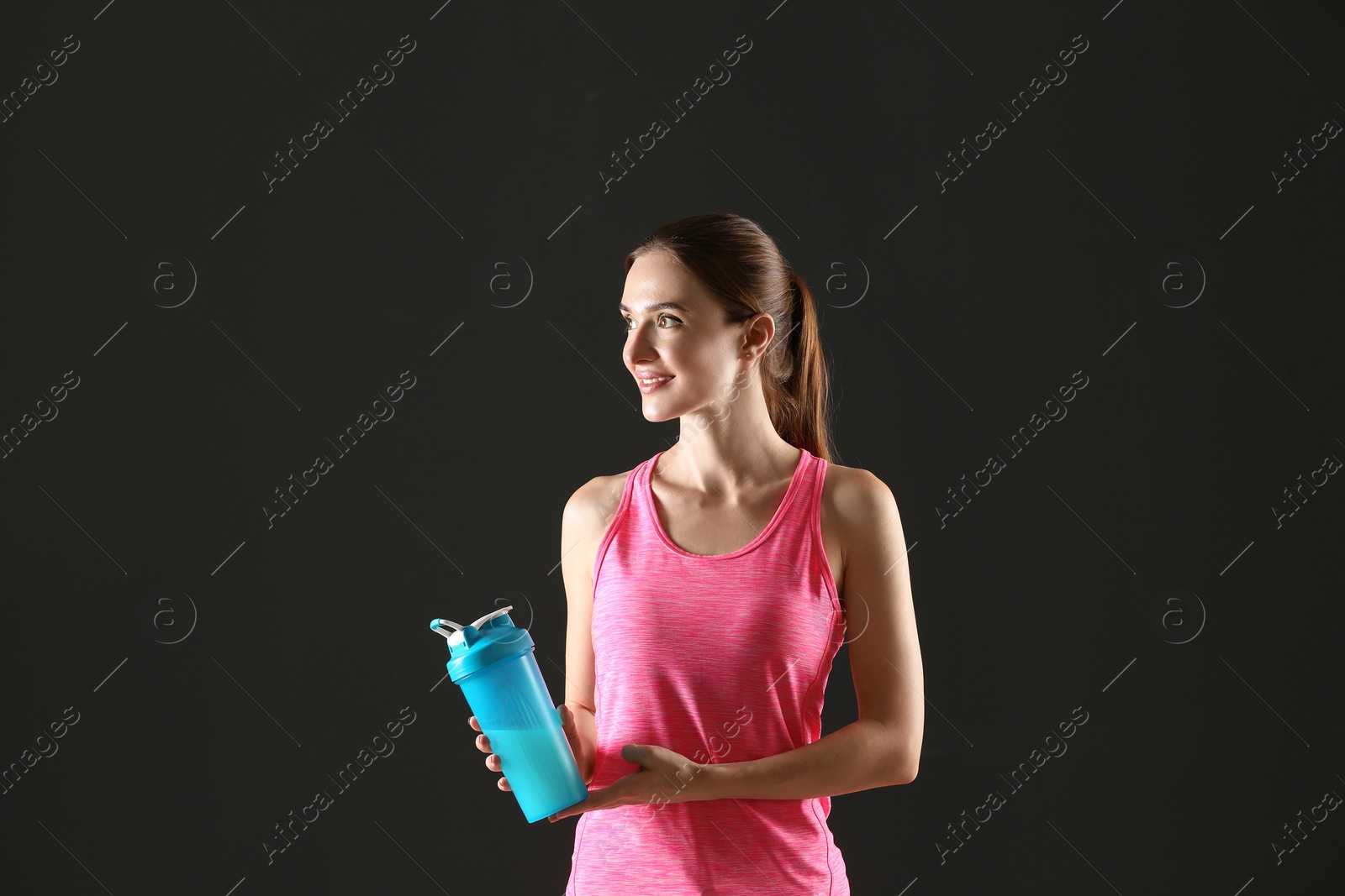 Photo of Athletic young woman with protein shake on black background