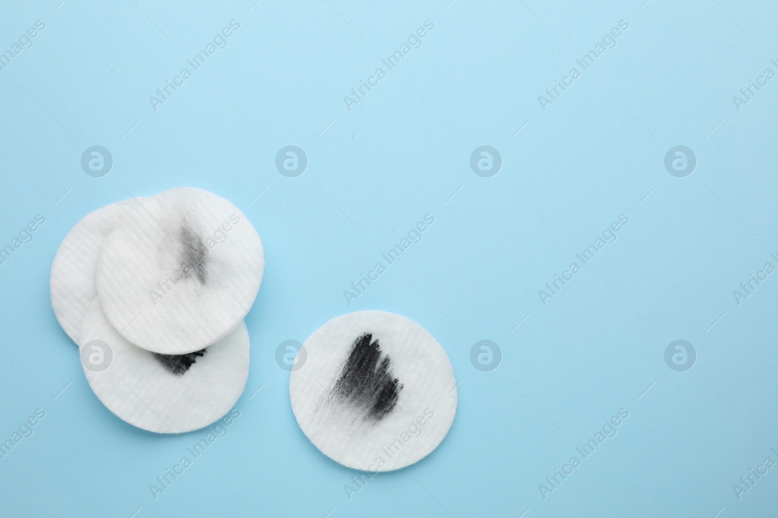 Photo of Dirty cotton pads after removing makeup on light blue background, flat lay. Space for text