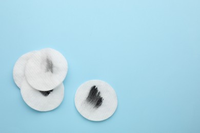 Photo of Dirty cotton pads after removing makeup on light blue background, flat lay. Space for text